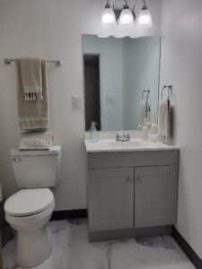 A bathroom with a toilet, sink and mirror.